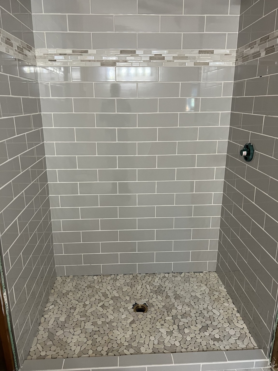 Shower tile with decorative mosaic band; project in progress